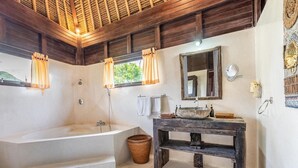 Een badkamer met een groot bad, een houten wastafelmeubel en een spiegel.