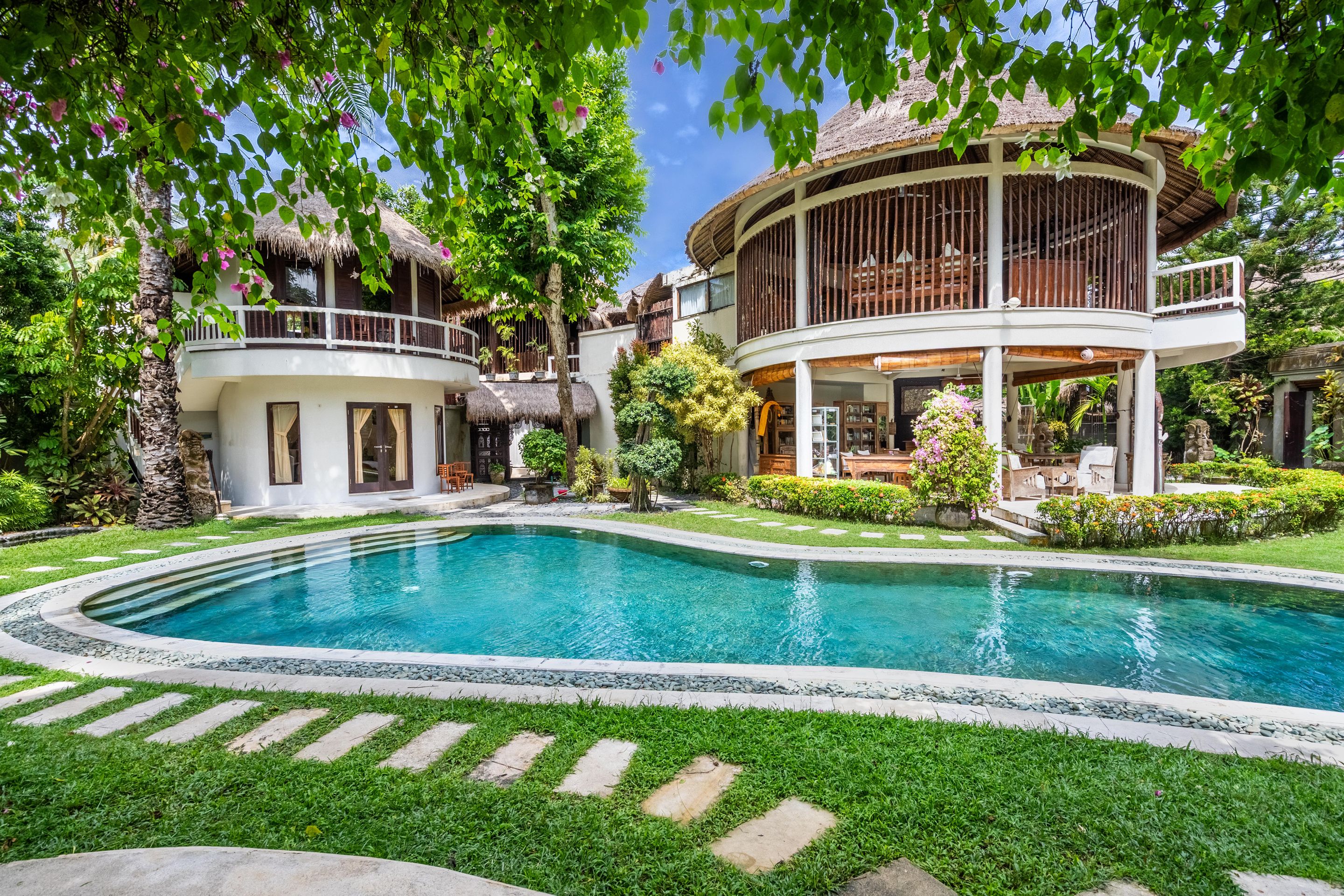 A pool surrounded by a well-maintained lawn and a two-story building with a balcony.