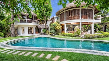 A pool surrounded by a well-maintained lawn and a two-story building with a balcony.