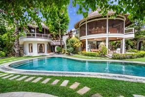 A pool surrounded by a well-maintained lawn and a two-story building with a balcony.