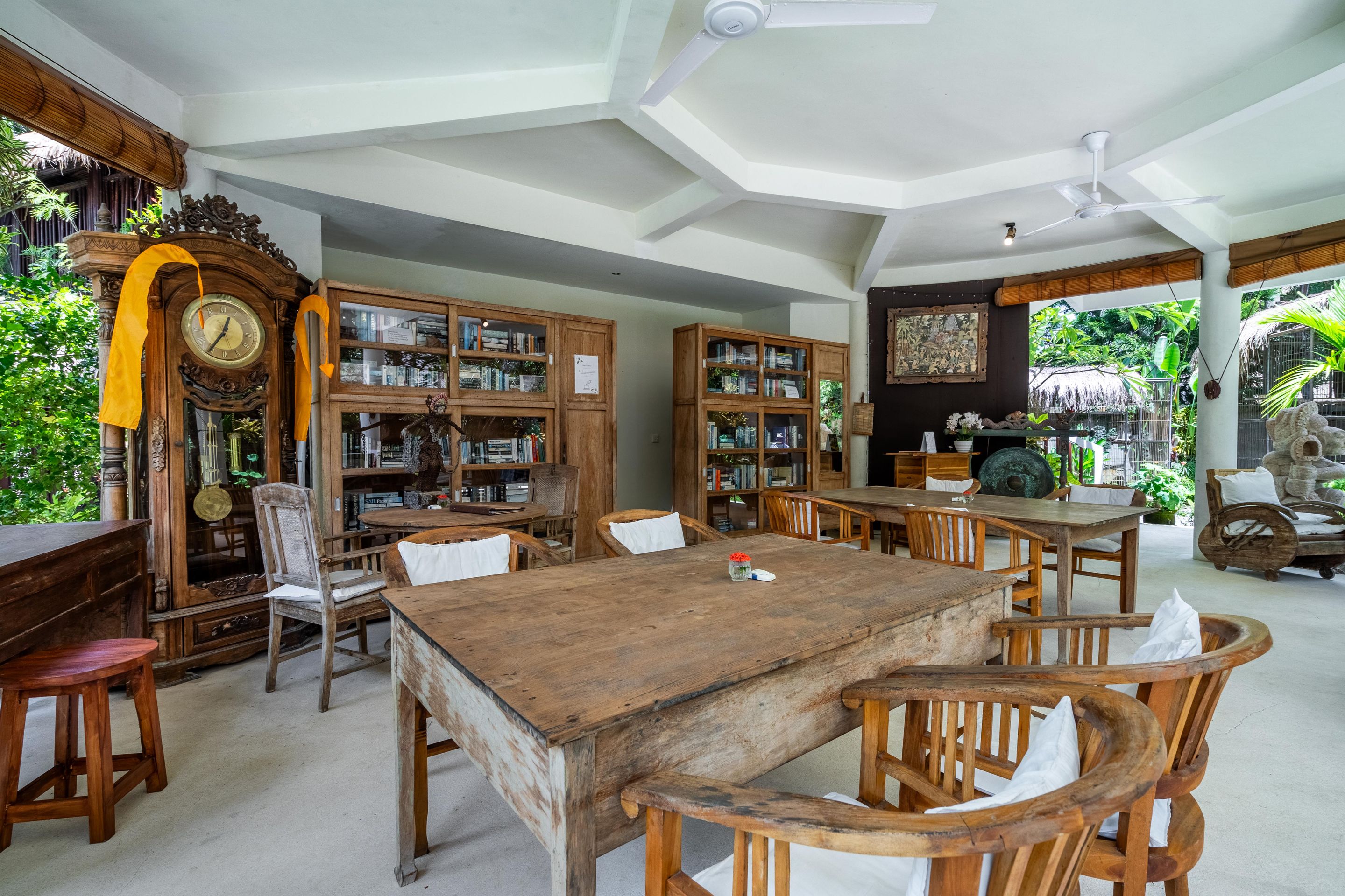 A spacious room with a large wooden table, multiple chairs, and a variety of bookshelves filled with books and decorative items.