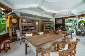 A spacious room with a large wooden table, multiple chairs, and a variety of bookshelves filled with books and decorative items.