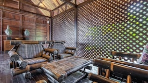 Interior de madera tradicional con muebles de bambú y un muro con celosías.