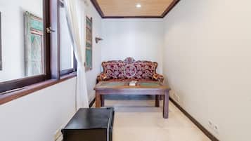Un estrecho pasillo con un banco de madera, una puerta con un tirador decorativo y una ventana con cortinas.