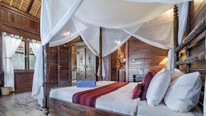 Una cama con dosel de madera, ropa de cama blanca y una manta de color rojo y negro.