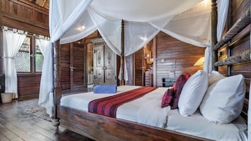 Una cama con dosel de madera, ropa de cama blanca y una manta de color rojo y negro.
