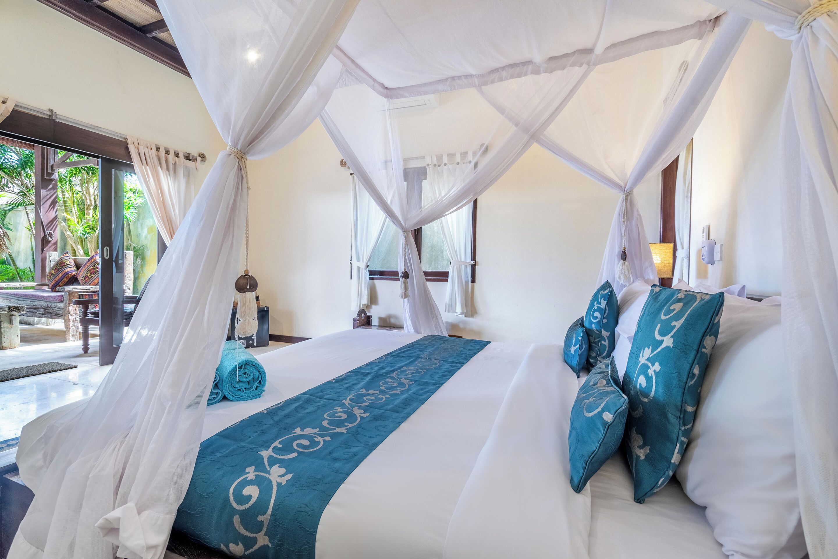 Un espacioso dormitorio con cama a dosel, un corredor azul decorativo y almohadas a juego.