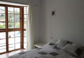 Une chambre à coucher avec un lit, une fenêtre avec des rideaux et une vue sur l’extérieur.