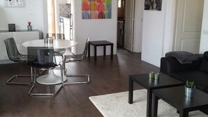 Un salon moderne comprenant un coin repas, un canapé noir et une petite table agrémentée d’une plante.