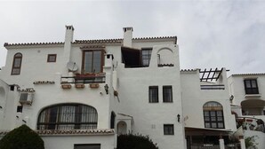 Un bâtiment blanc doté de nombreux balcons, de plusieurs antennes paraboliques et d’une grande fenêtre en arc de cercle.