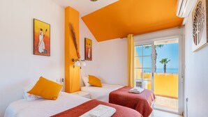 Hotelkamer met twee bedden, een balkon met uitzicht en kunstwerken aan de wanden.
