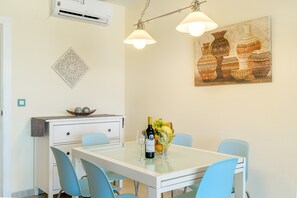 A dining area with a table, chairs, a wine bottle, and a fruit bowl.
