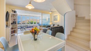 Een moderne woonkamer met een eethoek, een trap en uitzicht op zee.