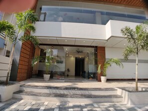 A modern building entrance with a glass facade, outdoor steps, and potted plants. - Hotel Yuvraj Palace (Bhopal)