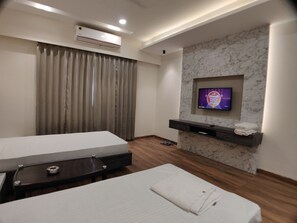 Habitación de hotel con cama, mesa de masaje, televisor montado en una pared de mármol y equipo de aire acondicionado.