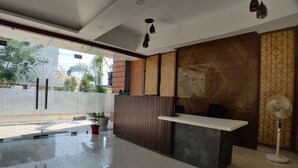 A modern reception area with a reception desk, a potted plant, and a standing fan. - Hotel Yuvraj Palace (Bhopal)