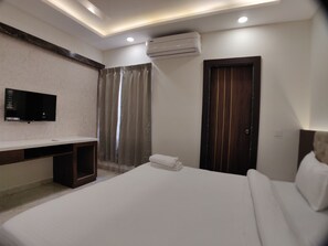 A hotel room with a bed, a TV mounted on the wall, a desk, and a wardrobe. - Hotel Yuvraj Palace (Bhopal)