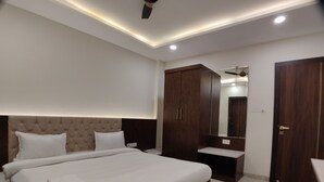 A modern bedroom with a large bed, a wardrobe, a vanity, and a ceiling fan. - Hotel Yuvraj Palace (Bhopal)