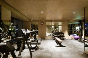 Un gimnasio con cintas de correr, mancuernas y pelotas de ejercicio.