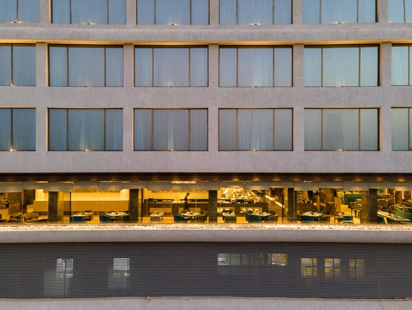 Un hotel de varios pisos, con amplias ventanas y fachada de vidrio en la planta baja.