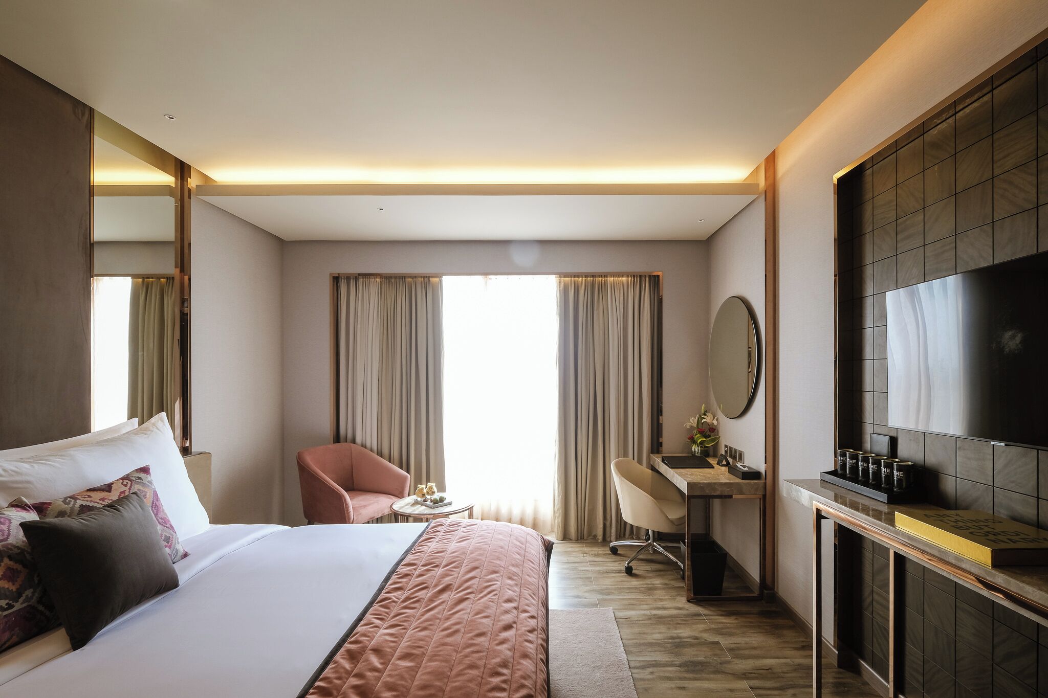 A hotel room with a bed, a desk, a chair, a TV, and a large window with curtains.