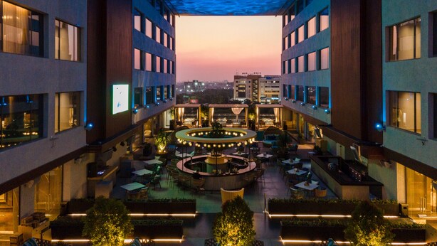 A modern hotel atrium with a central courtyard, multiple floors, and a view of the cityscape at dusk. - The Park Indore (Indore)