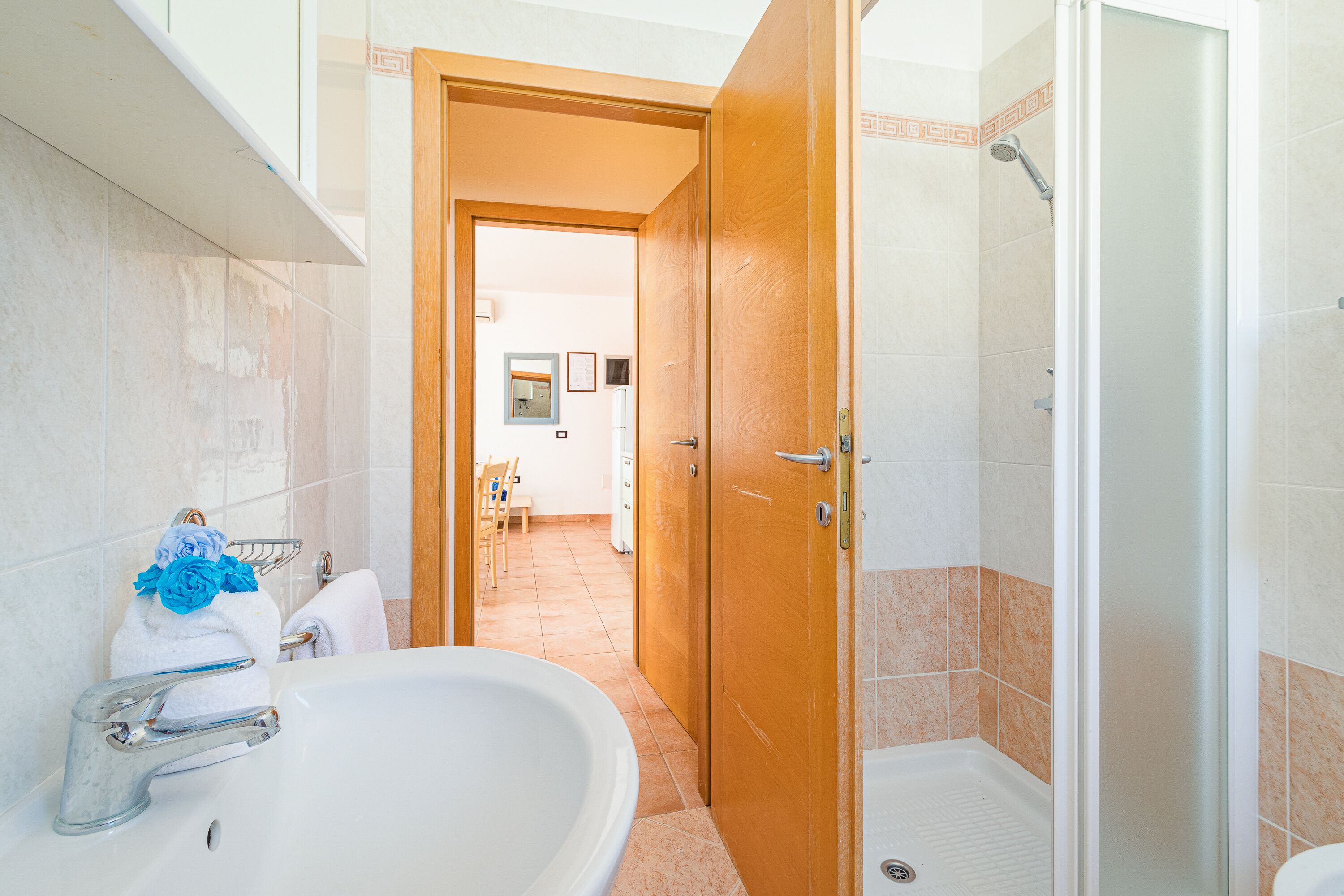 Un baño con bañera, ducha y una puerta de madera que da a otra habitación.