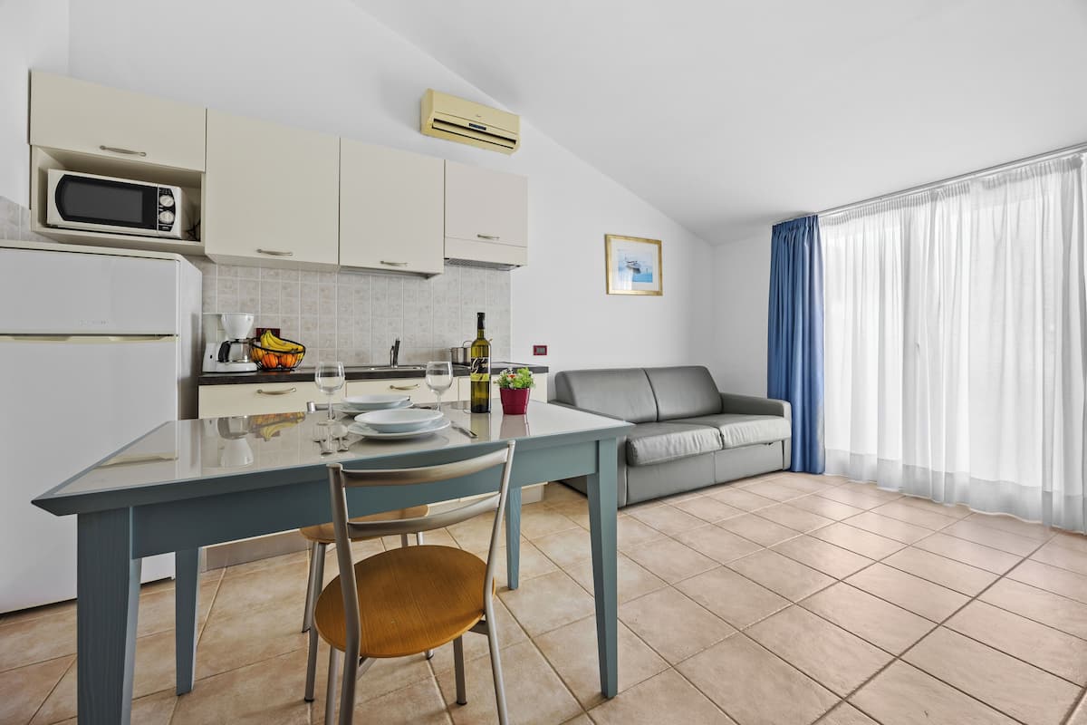 A modern kitchen with a dining table, chairs, and a grey sofa.
