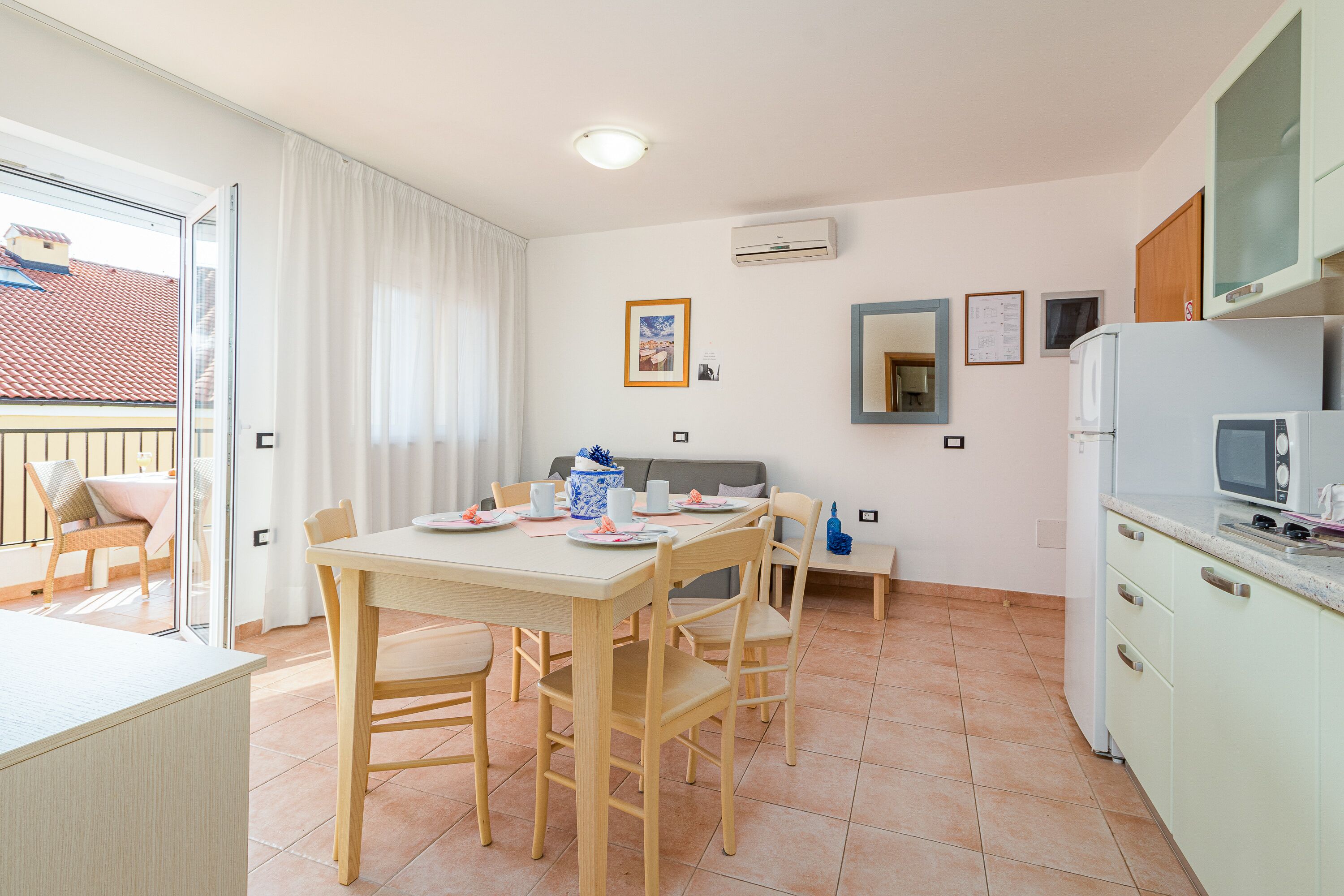 A compact kitchen with a dining area, a small refrigerator, and a window with curtains.