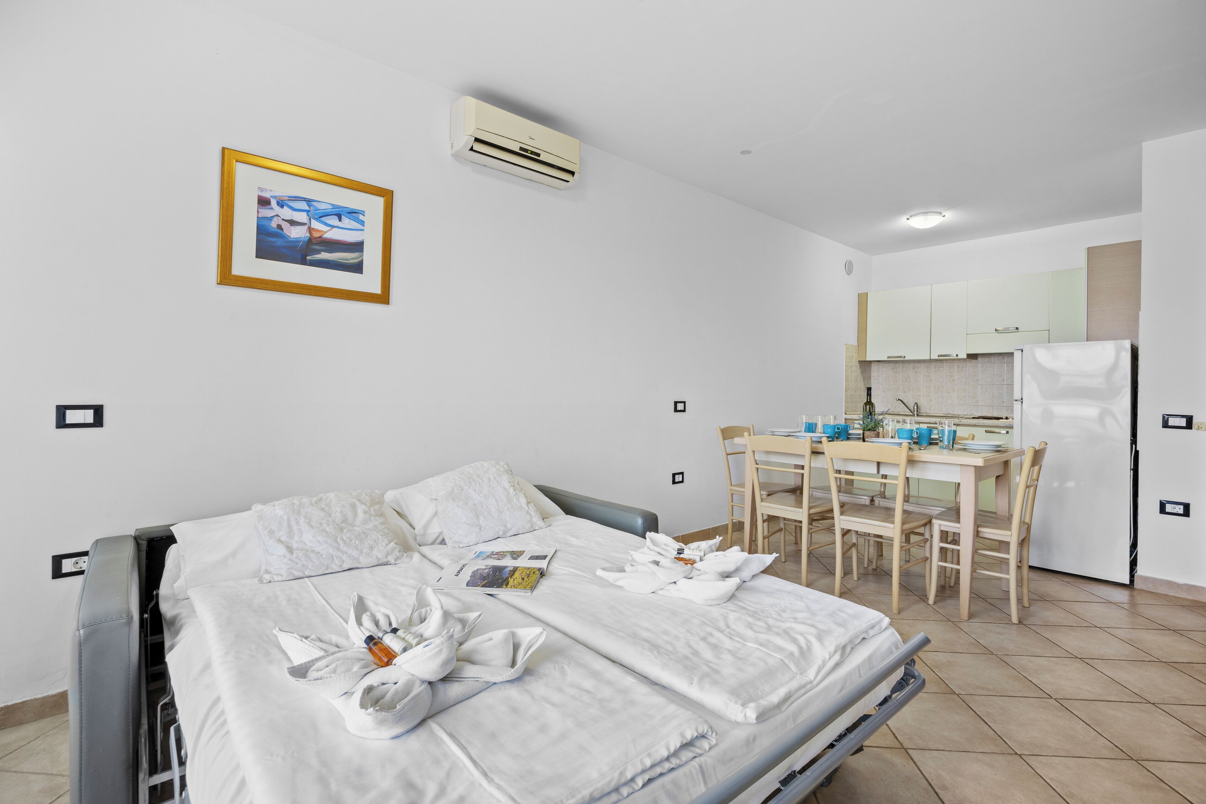 Ett hotellrum med en säng, ett matbord med stolar, ett köksutrymme och en luftkonditioneringsanläggning.