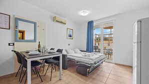 A modern bedroom with a bed, a dining table with chairs, and a small balcony with a table and chairs. - Residence Kamenjak (Medulin)