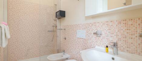 A bathroom with a shower, bidet, toilet, and sink.