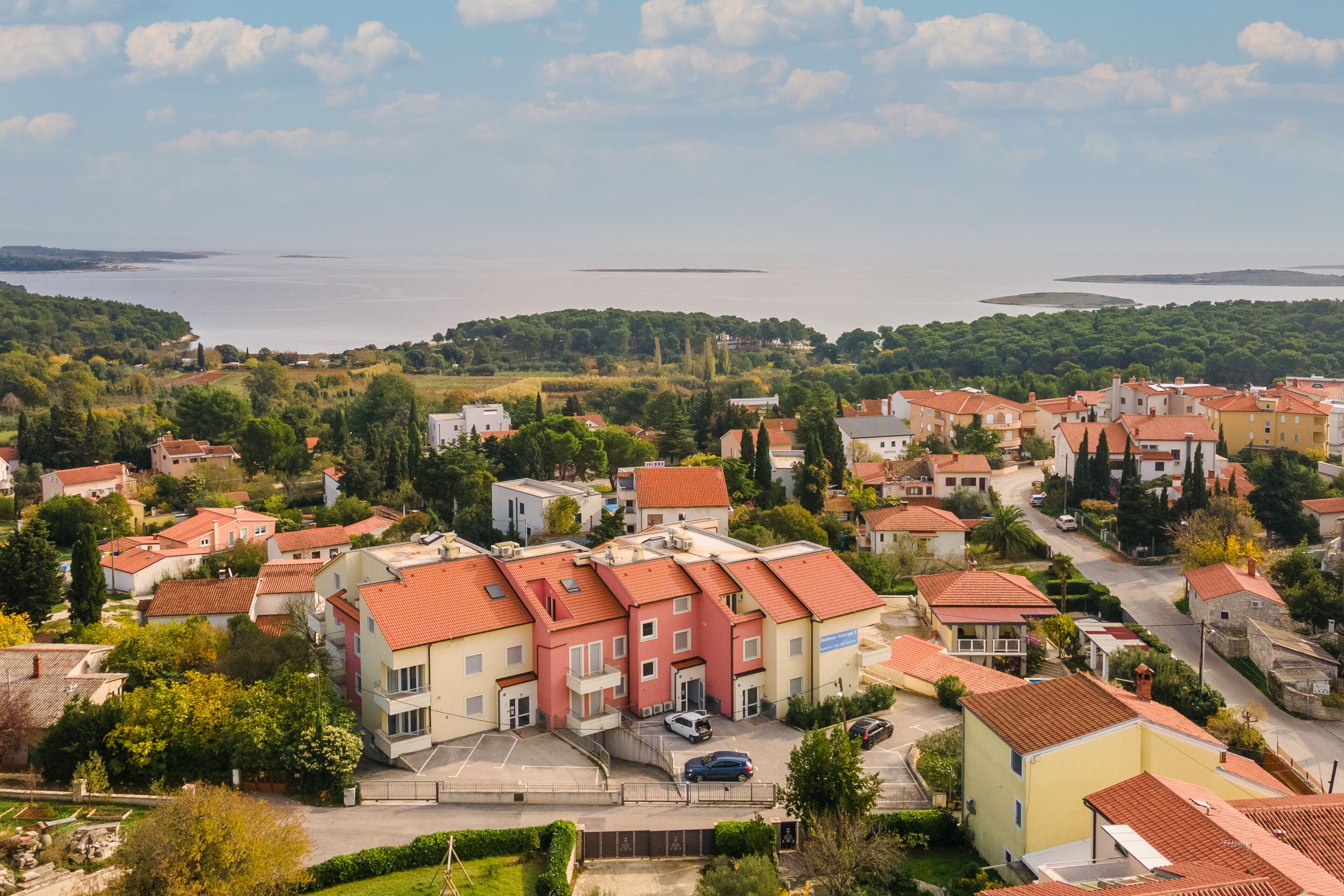 A residential area with houses, a road, and a body of water in the background.
