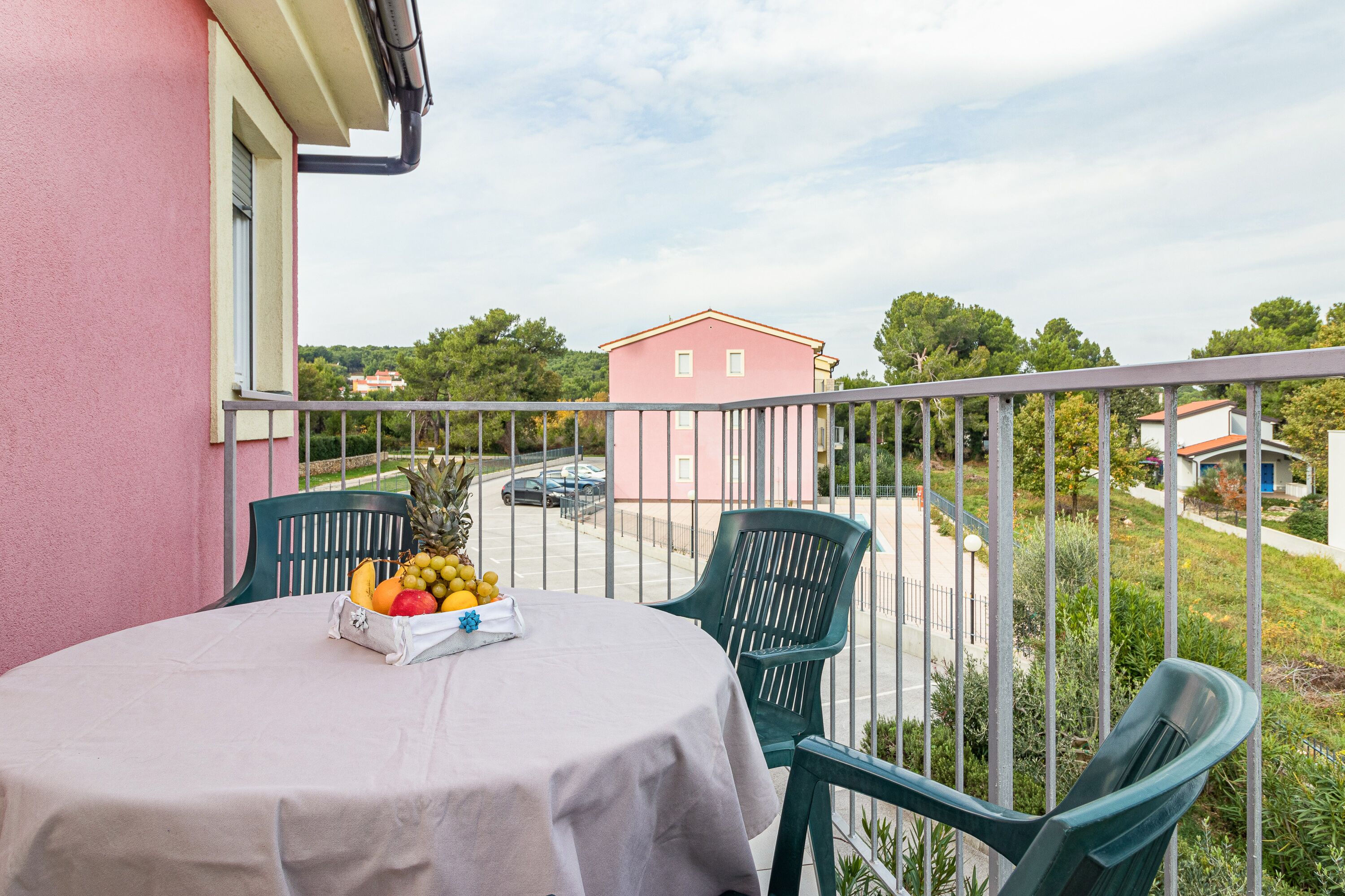 A balcony with a table set for two, featuring a fruit bowl.