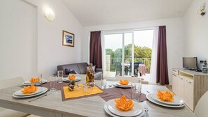 A dining area with a table set for four, a sofa, and a view of the outdoors. - Residence Kamenjak (Medulin)