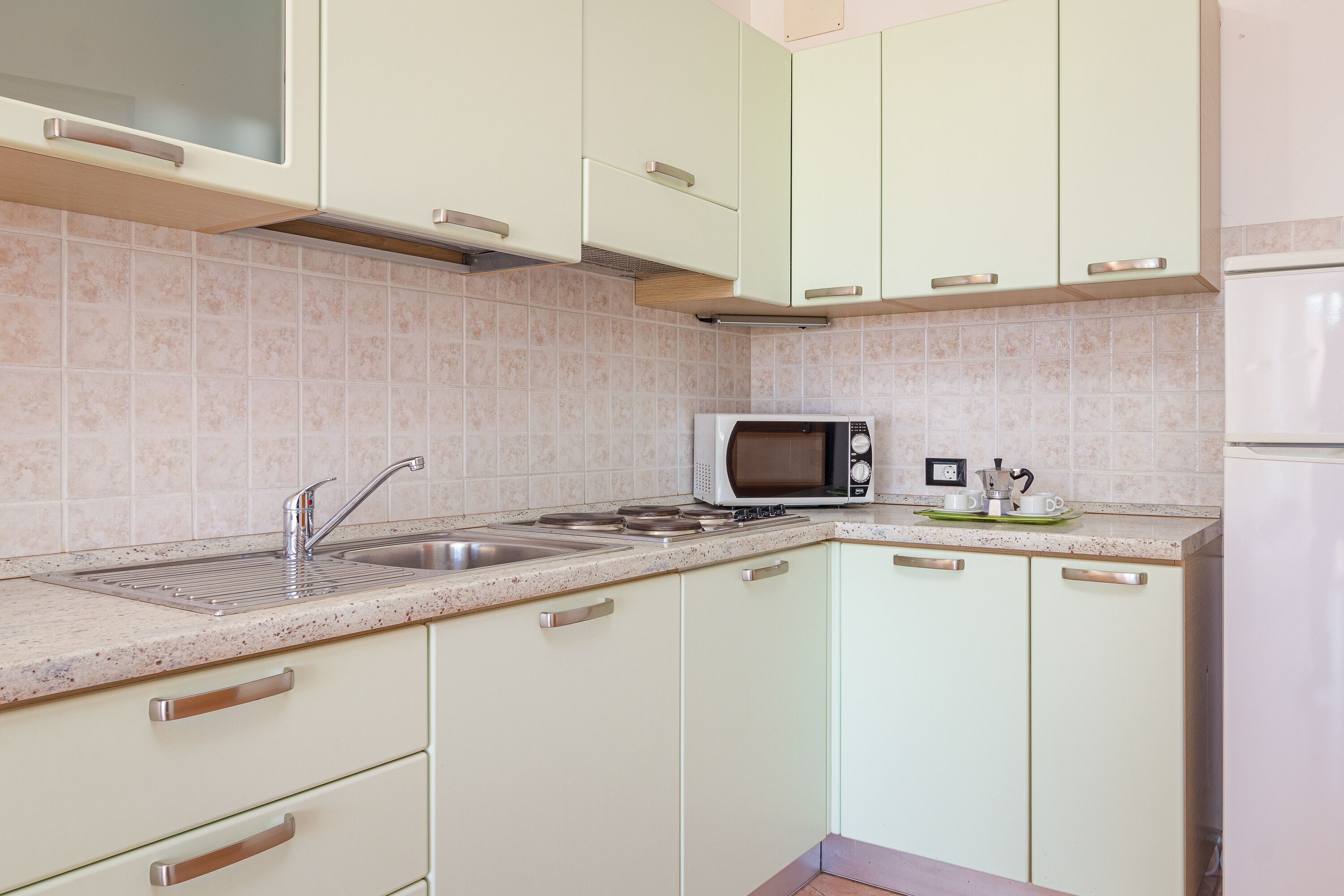 Una cucina con forno a microonde, lavandino e piano cottura.