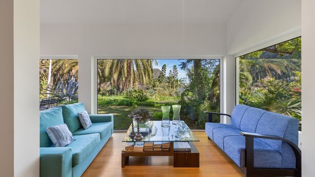 A modern living room with a glass coffee table, two sofas, and a view of a lush garden. - Finca El Dragonal with Mountain View, Garden & Wi-Fi (Las Meleguinas, Santa Brígida)