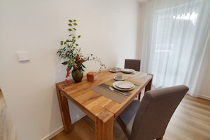 Une table à manger avec un set de table, des assiettes, des couverts et un vase contenant une plante.