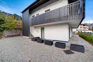 Un bâtiment moderne doté d’un balcon, d’une porte et d’un escalier menant à un niveau supérieur.