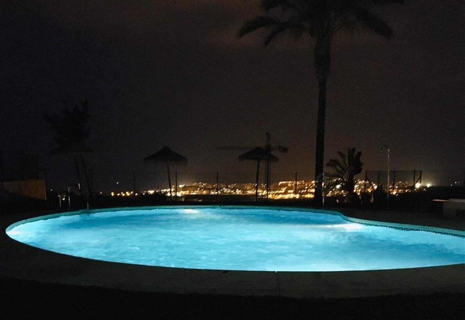 Une piscine nocturne offrant une vue sur le paysage urbain en arrière-plan.