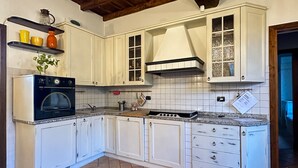 A kitchen with white cabinets, a stove, and a microwave. - Appartamento in storica Cascina Lombarda Cusago (Cascina Cusago di Sotto)