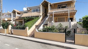 Un immeuble résidentiel à plusieurs étages, doté d’un escalier, de balcons et d’une entrée sécurisée par un portail.