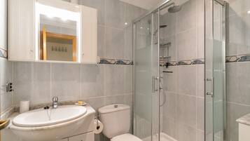 A bathroom with a glass shower enclosure, a sink, a toilet, and a cabinet with a mirror.