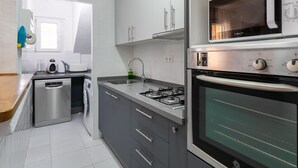 Ett modernt kök med vitvaror i rostfritt stål, diskmaskin, inbyggd ugn och mikrovågsugn.