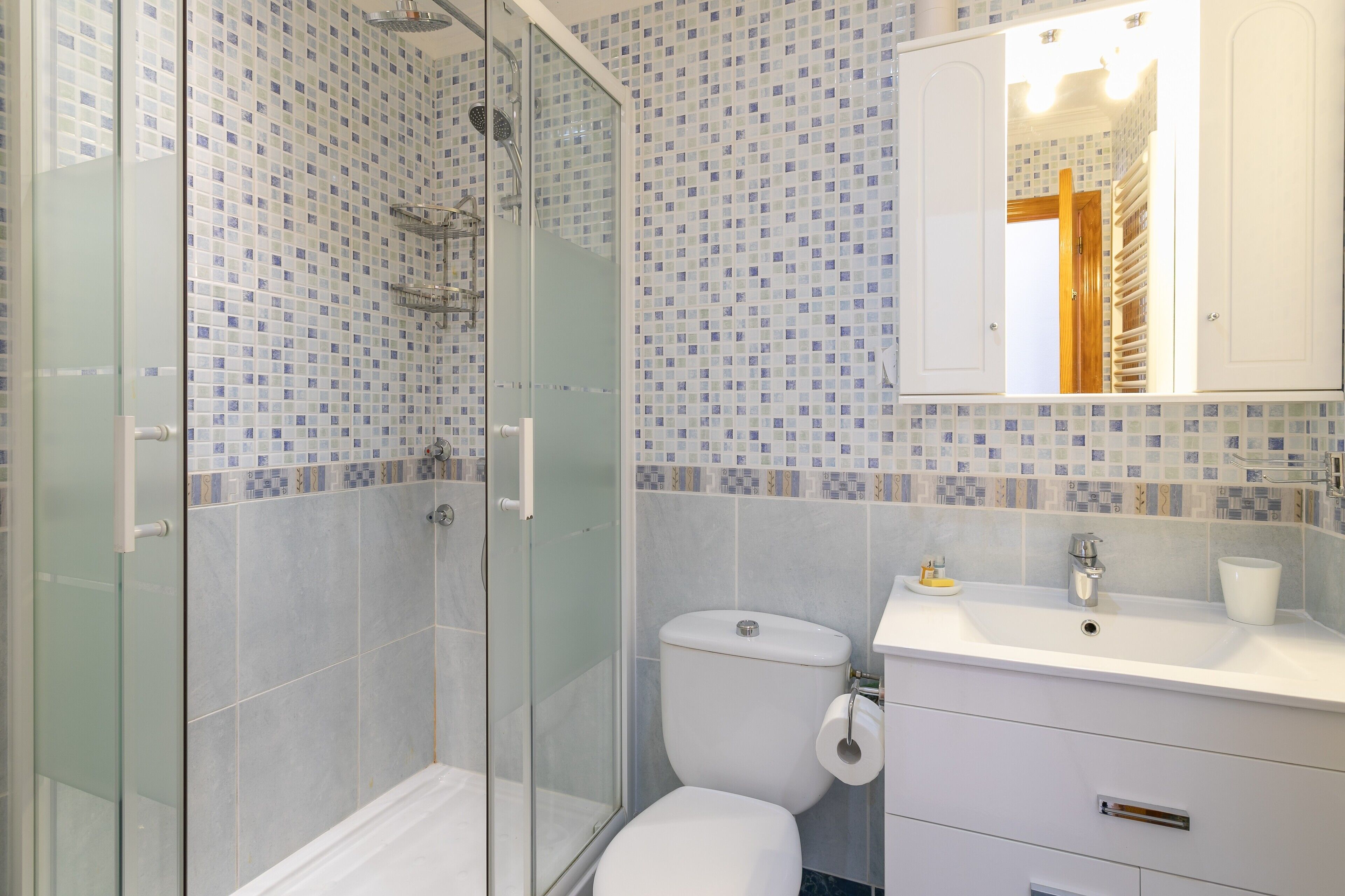 Un bagno con doccia vetro, un water e un lavandino con specchio sopra.