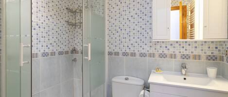Un bagno con doccia vetro, un water e un lavandino con specchio sopra.
