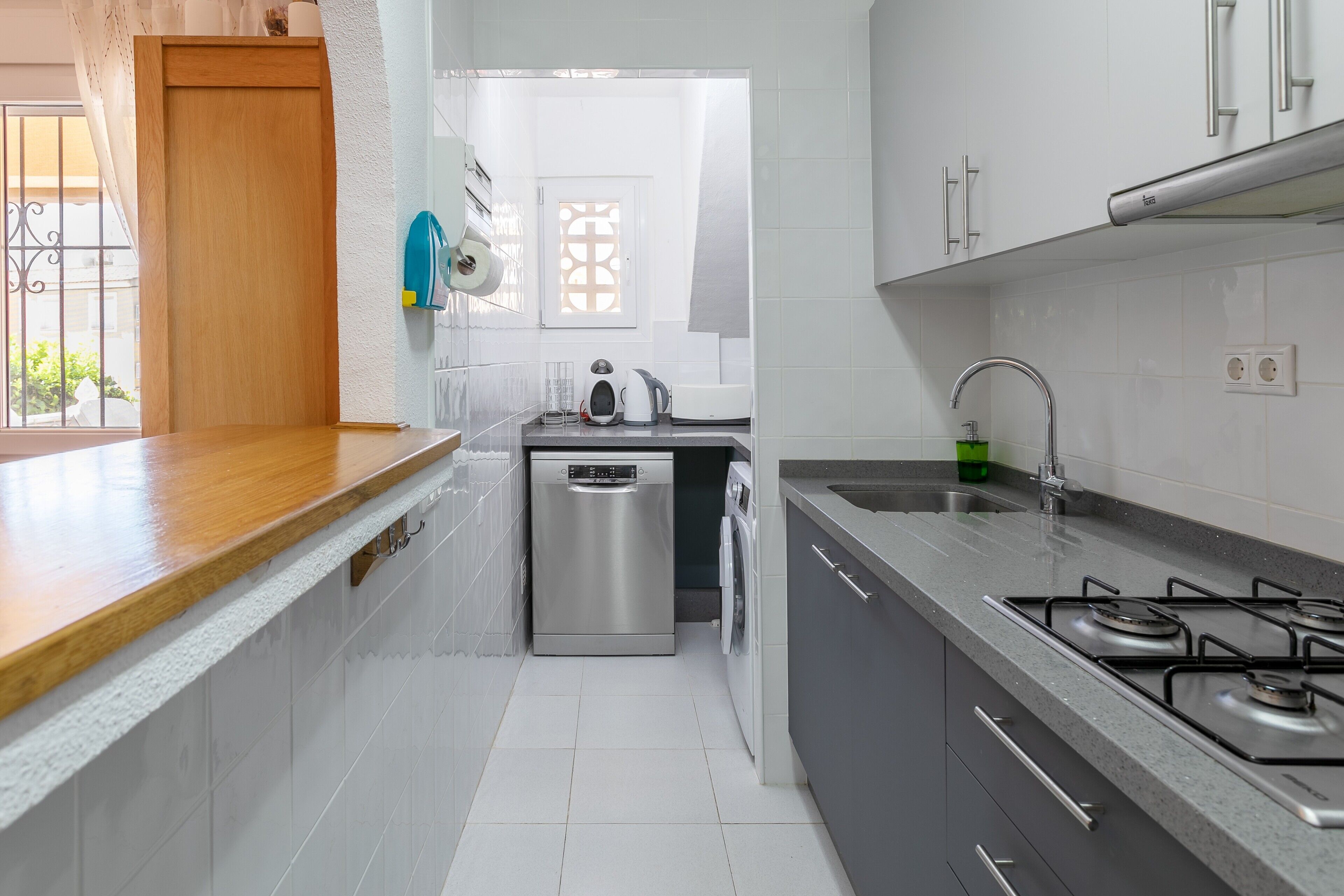 Une cuisine compacte équipée d’un lave-vaisselle, d’une machine à laver, d’un évier et d’une cuisinière.
