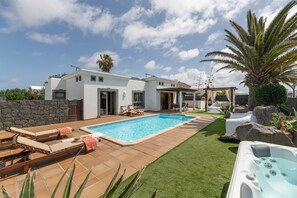 Een moderne woning met een zwembad, buitenmeubilair en een jacuzzi.