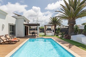 A swimming pool with lounge chairs, a patio area, and a palm tree. - Vacation Villa 'Carabela 83' with Mountain View, Private Pool and Wi-Fi (Playa Blanca)