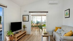 A modern living room with a flat-screen TV, a sofa, a coffee table, and a dining area with a table and chairs. - Vacation home 'Los Cipreses' with Mountain Views, Indoor Pool, Garden & Wi-Fi (Ingenio)
